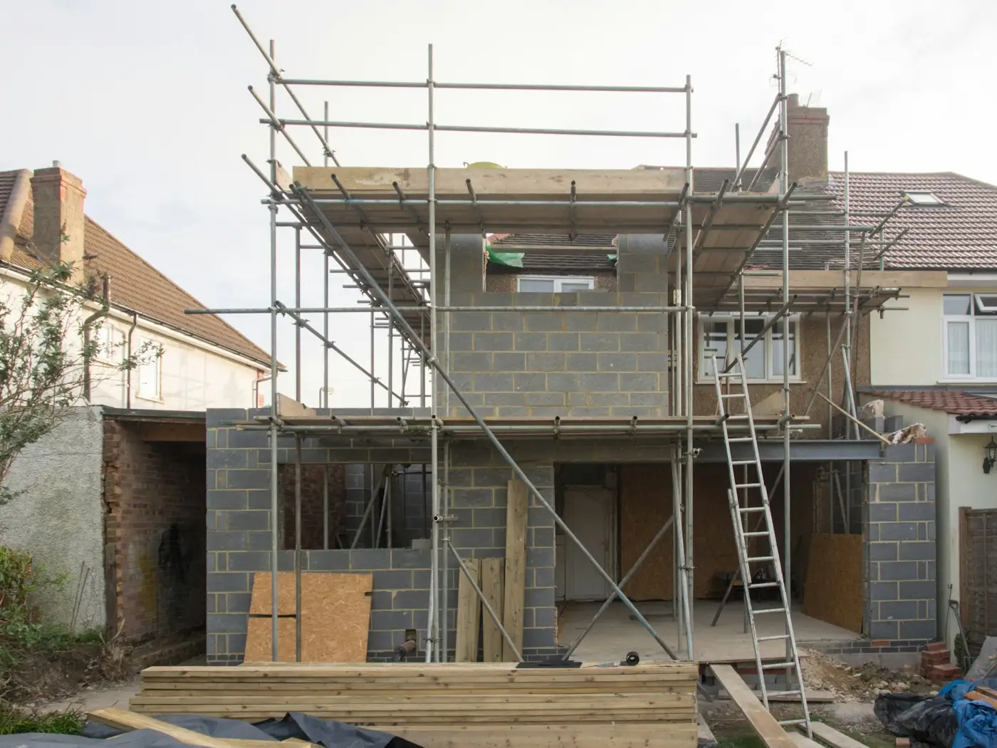 Scaffolding around a house extension with a ladder up to the first lift