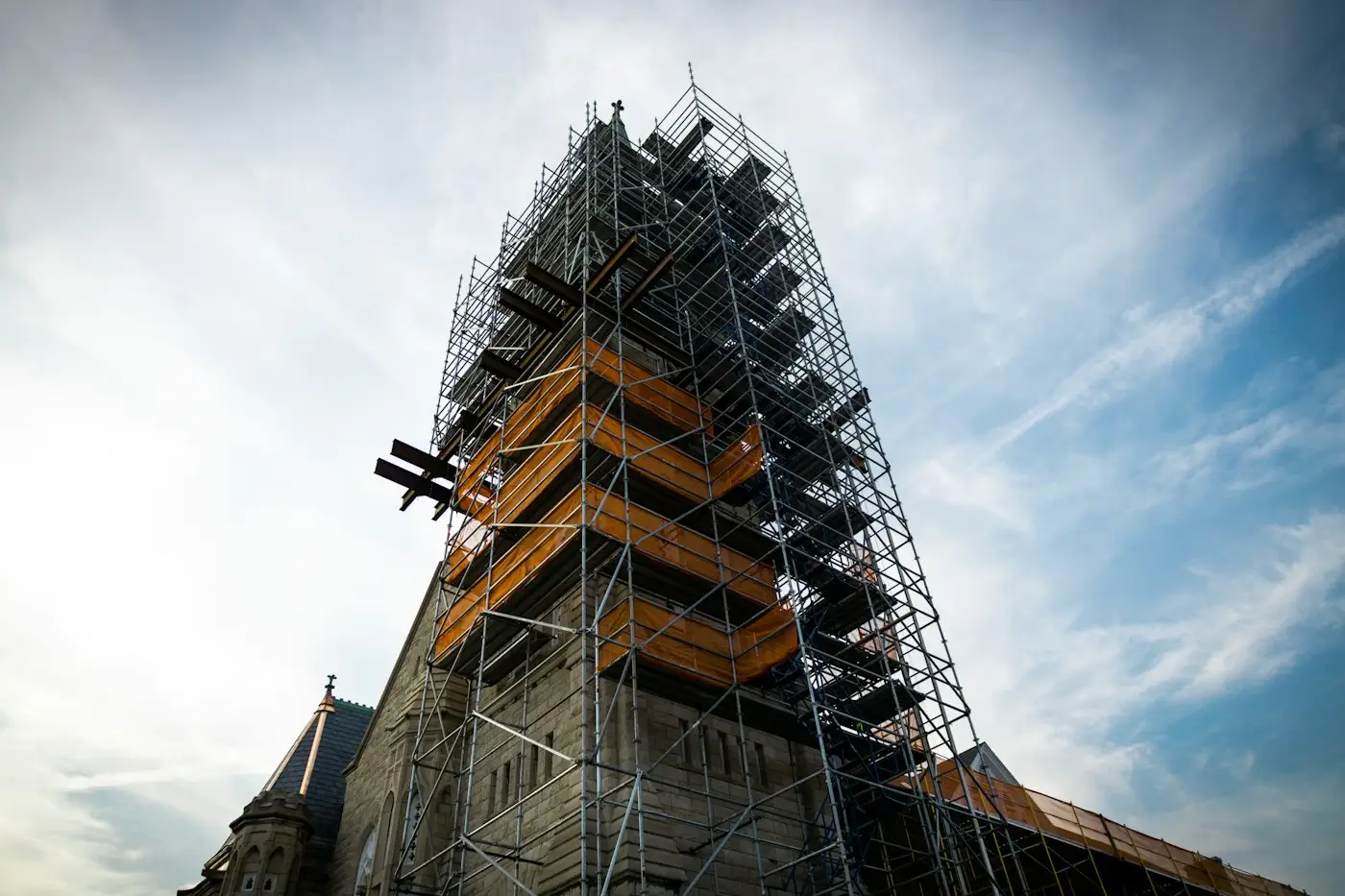 A stone church spire wrapped in scaffolding