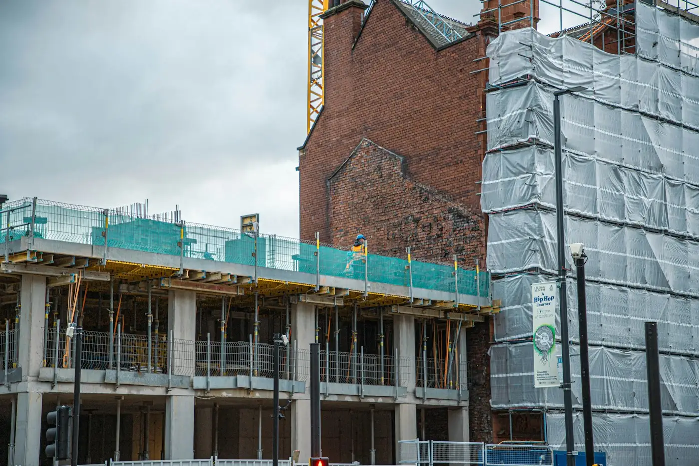 A building wrapped in white scaffold sheeting next to a building site