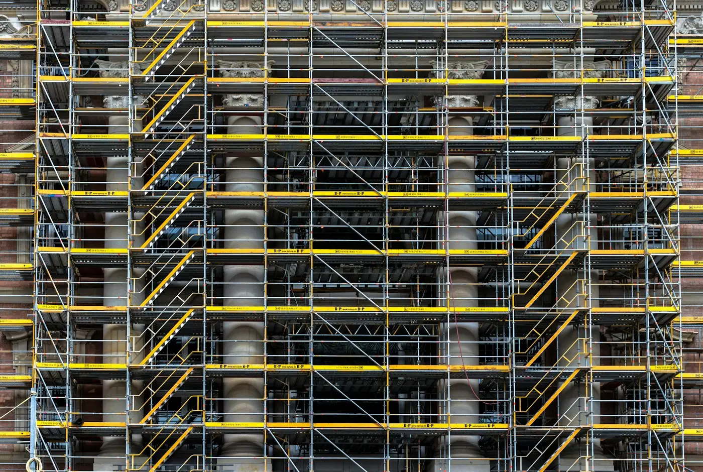 A full-height scaffold on a large building, with yellow stair towers running up it